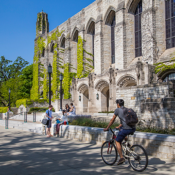 Student riding bike past Northwestern University Deering Library