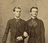 Two men in Victorian era linking arms 